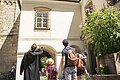 Eine Familie steht mit einem Mönch vor dem Eingang zum Kloster Plankstetten. Der Mönch erklärt der Familie etwas von der Geschichte des Gebäudes. Er hat seinen Arm gehoben und zeigt auf etwas.