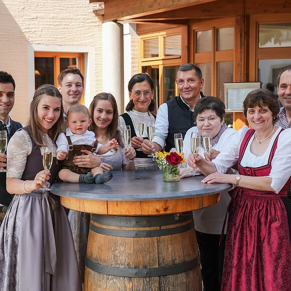 Das gesamte Team des Landgasthofes Euringer ist in Tracht gekleidet und steht hinter einem Stehtisch mit einem Glas Bier in der Hand.