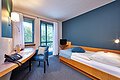 Einzelzimmer mit Holz Bett und verschiedenen blauen Details.