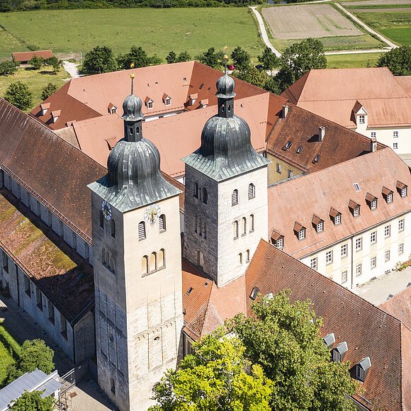 Kloster Plankstetten Luftaufnahme eines historischen Gebäudekomplexes mit zwei Kirchtürmen und roten Ziegeldächern in ländlicher Umgebung.