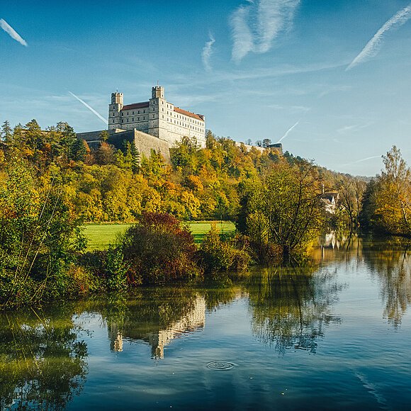 In der linken oberen Ecke thront die Willibaldsburg, ein hellgrauer, rechteckiger Bau mit vielen Fenstern und zwei Türmen an den vorderen Ecken.  Direkt davor zeigt sich ein Teil der schützenden Bastionsmauer.  Die Burg selbst steht auf einem bewaldeten Berg. Die untere Hälfte des Bildes wird von dem Fluss „Altmühl” eingenommen, die sich im Tal um die Willbaldsburg schlängelt.