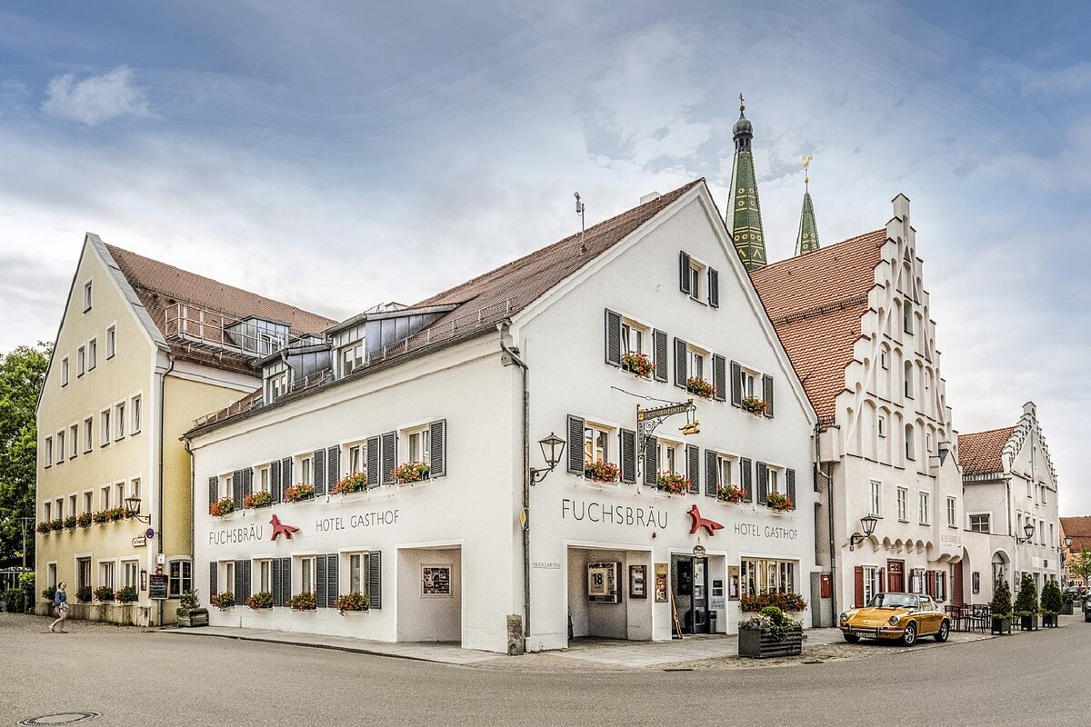 Das Hotel mit 3 Häusern an einer Straßenecke ist zu sehen. Im Hintergrund noch die beiden Türme der Stadtpfarrkirche.